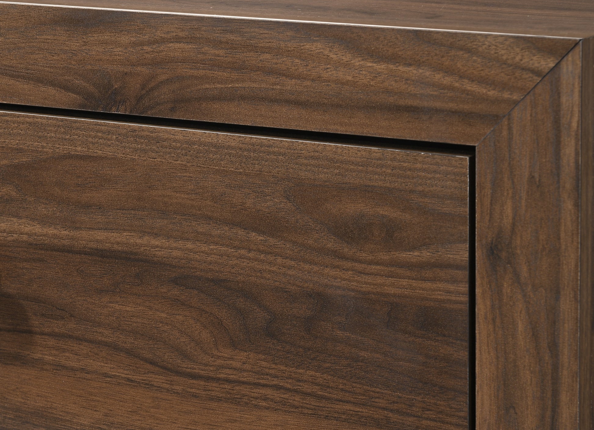 Closeup of dark walnut wood grain on a modern dresser drawer front