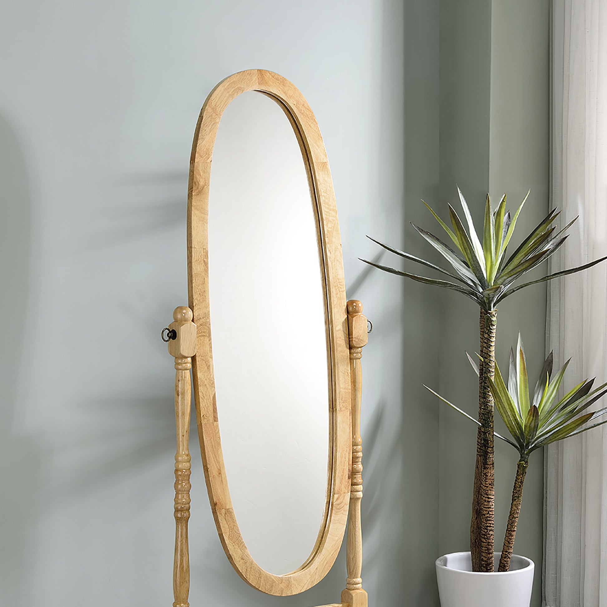 Oval standing cheval mirror with a light wood frame and ornate carved details