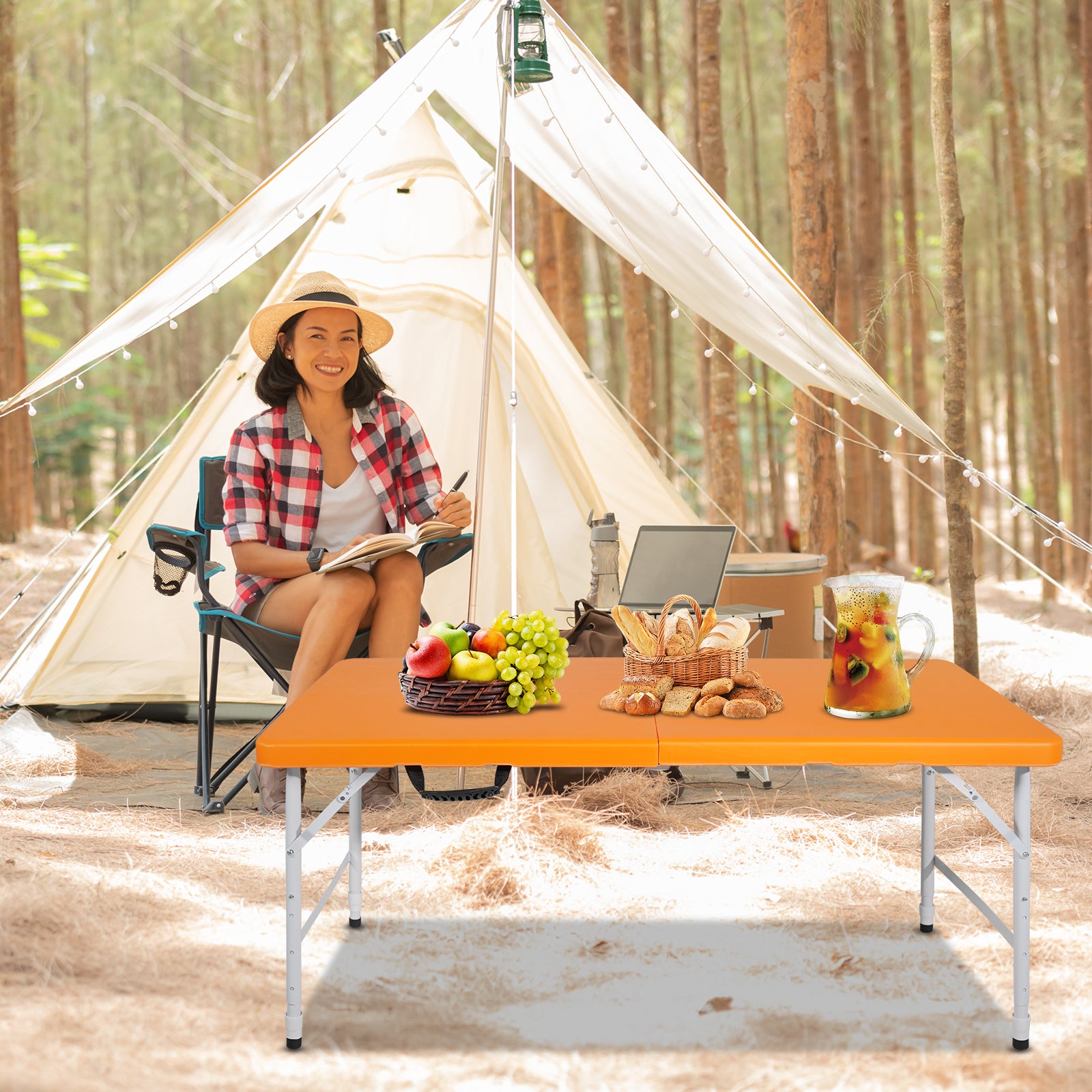 Orange portable folding picnic table set up in a forest with food and drinks