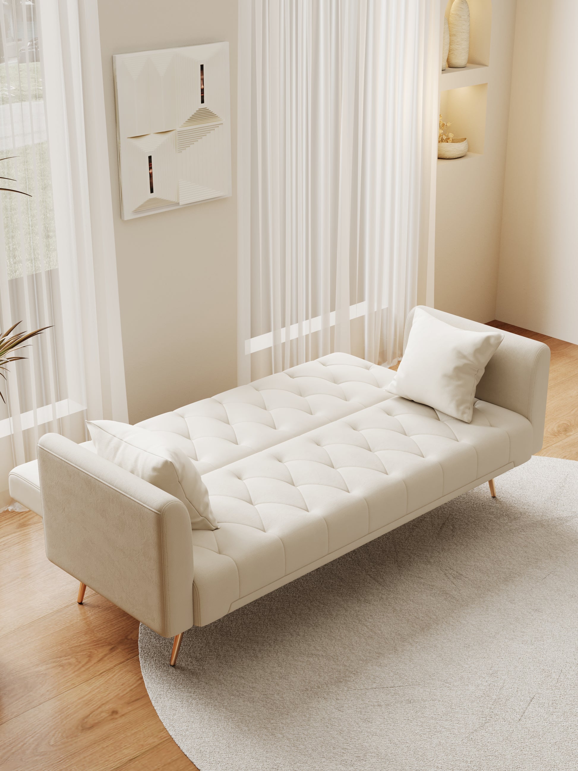 Cream upholstered tufted sofa bed with gold legs in a bright living room