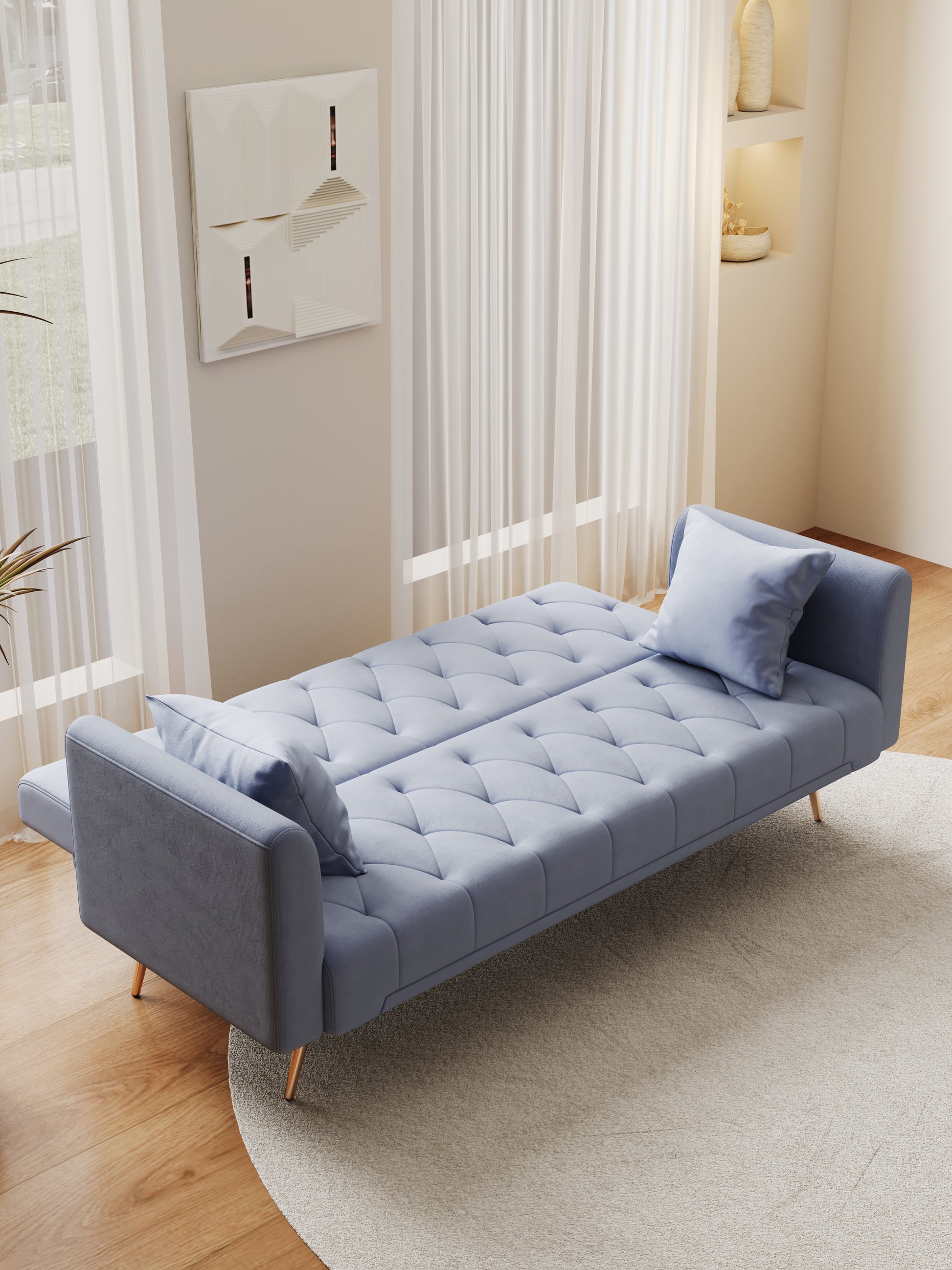 Tufted light blue velvet sofa bed with gold legs and matching pillow ideal for small apartments