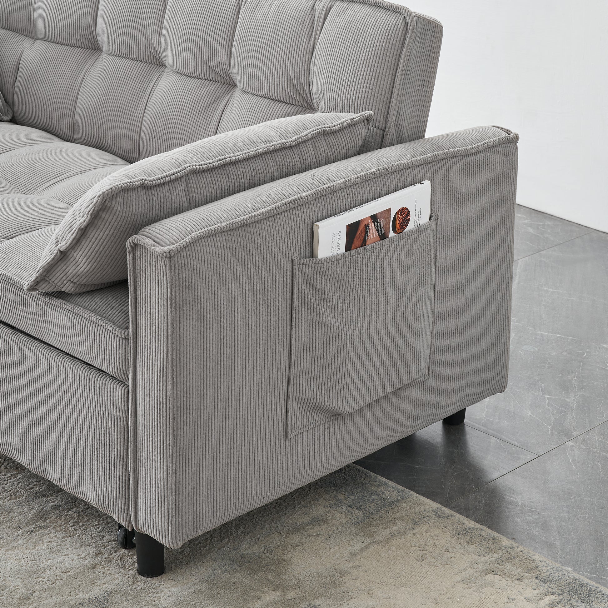 Close up of grey corduroy sofa arm with a convenient side pocket holding a magazine