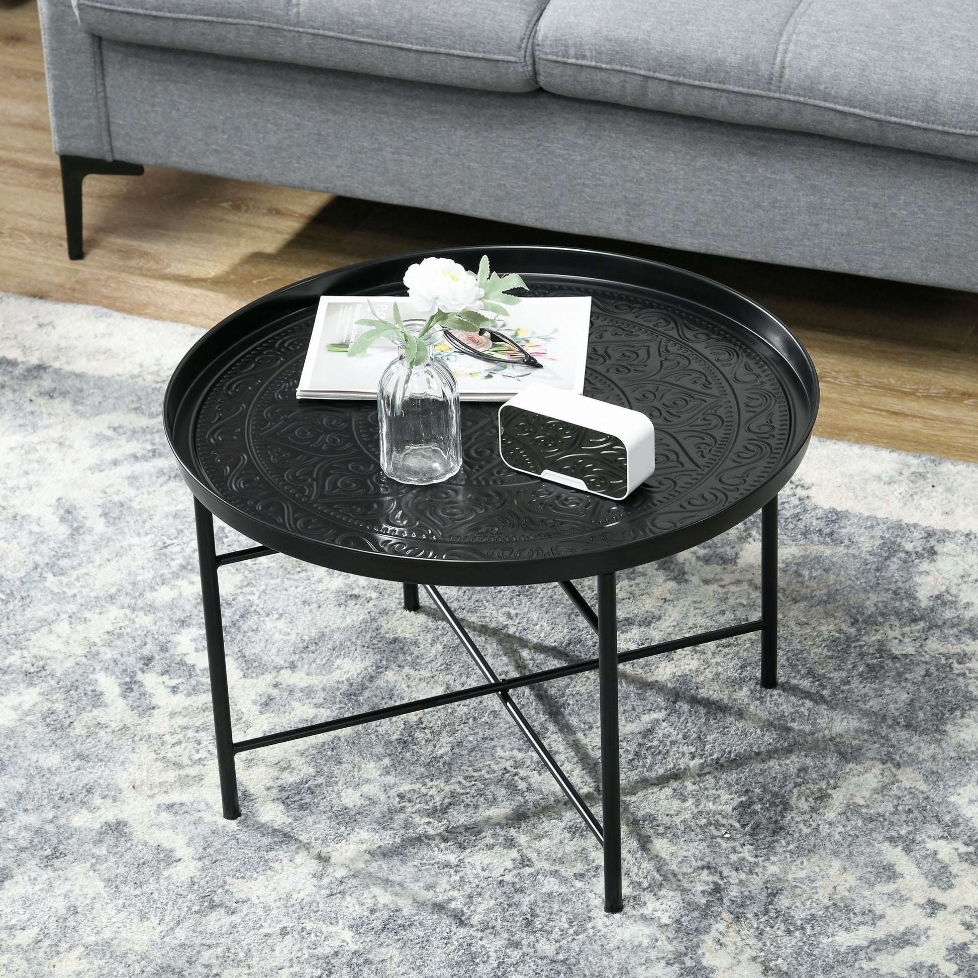 Black metal round tray table with ornate embossed pattern