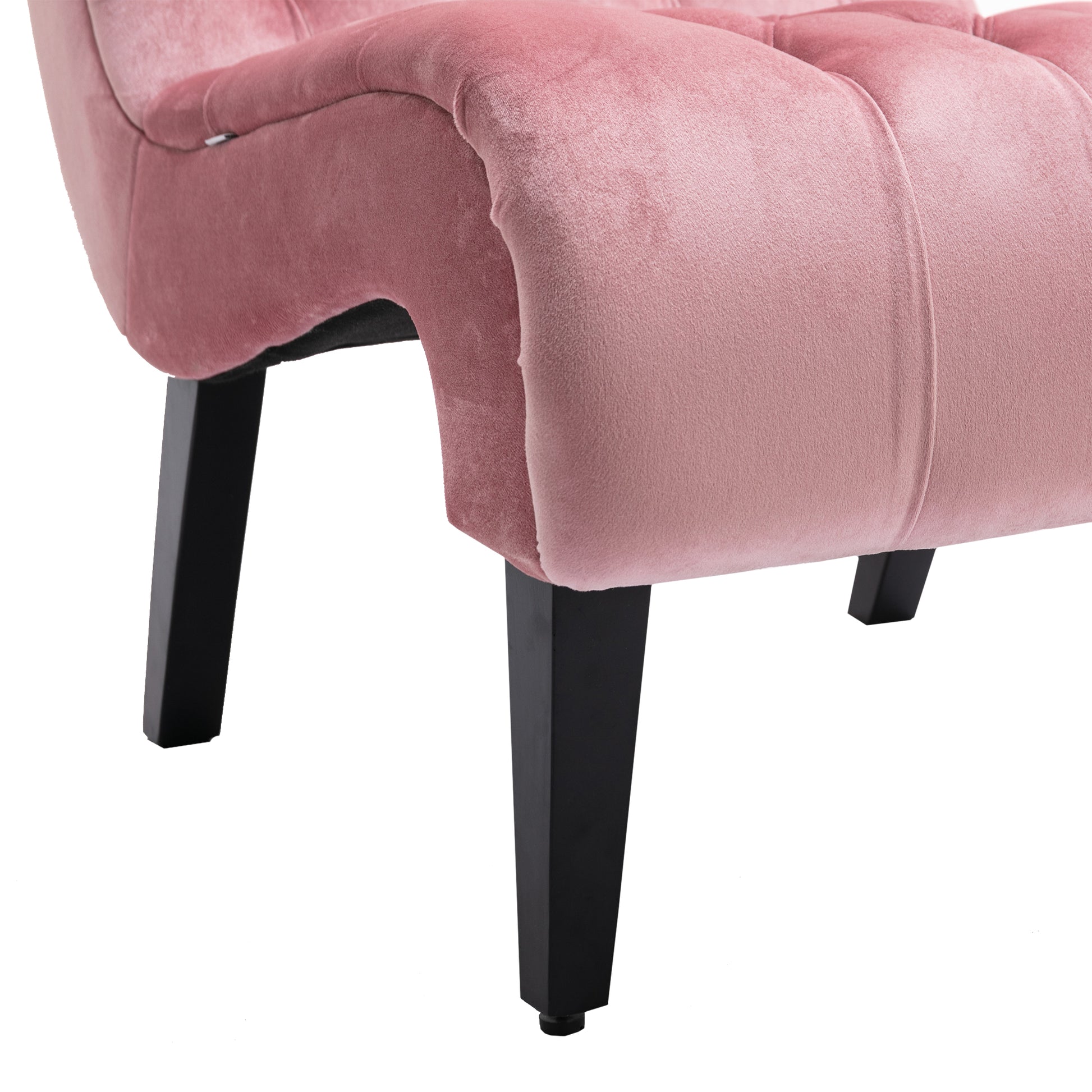 Closeup of tufted blush velvet armchair armrest and black tapered legs