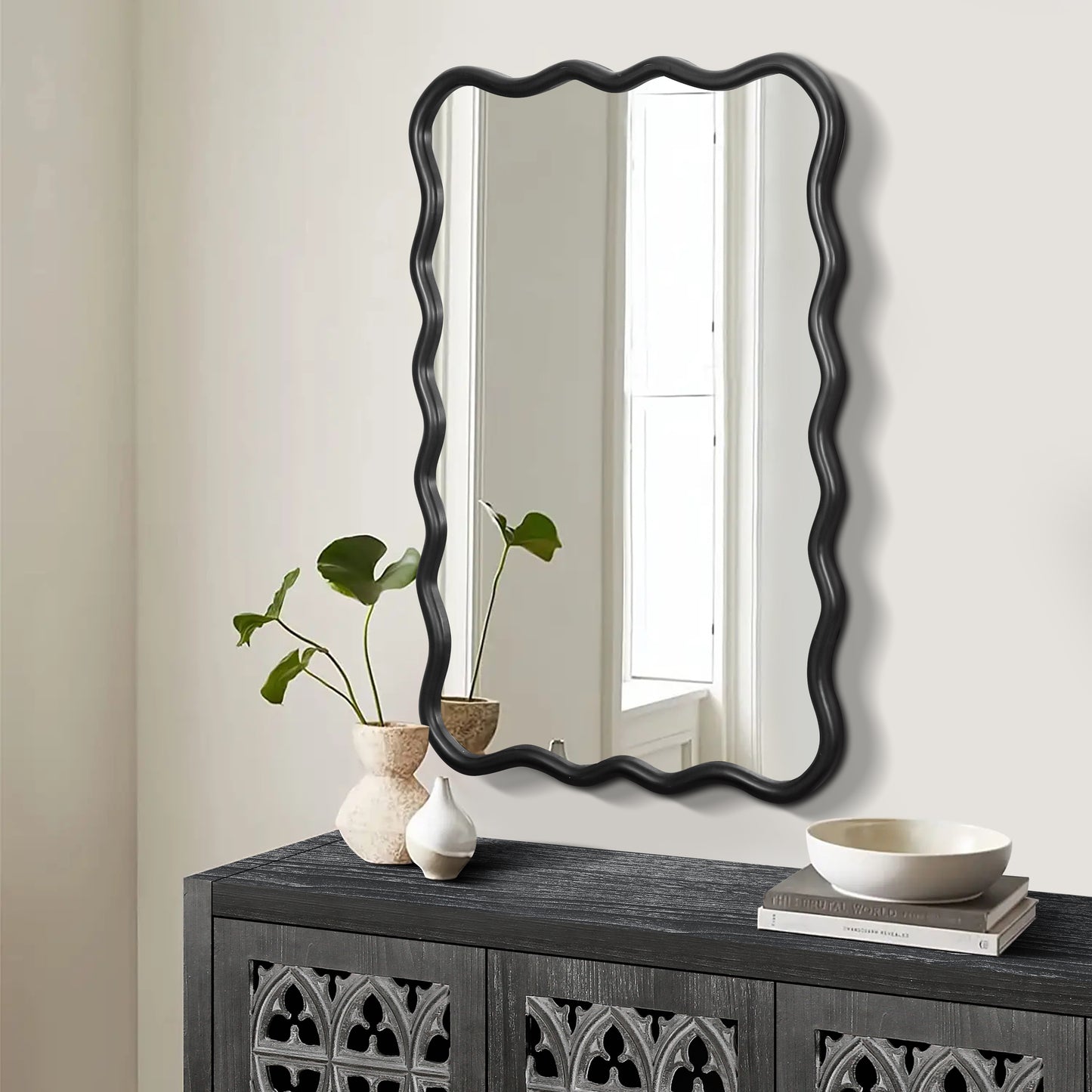 Black wavy mirror with a playful undulating frame perfect for a modern entryway accent