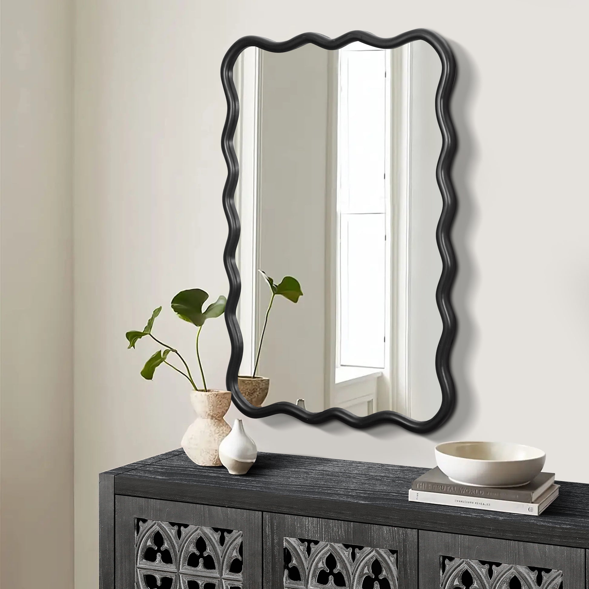 Black wavy mirror with a playful undulating frame perfect for a modern entryway accent