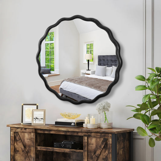 Black scalloped accent mirror with wavy frame adding flair to a bedroom