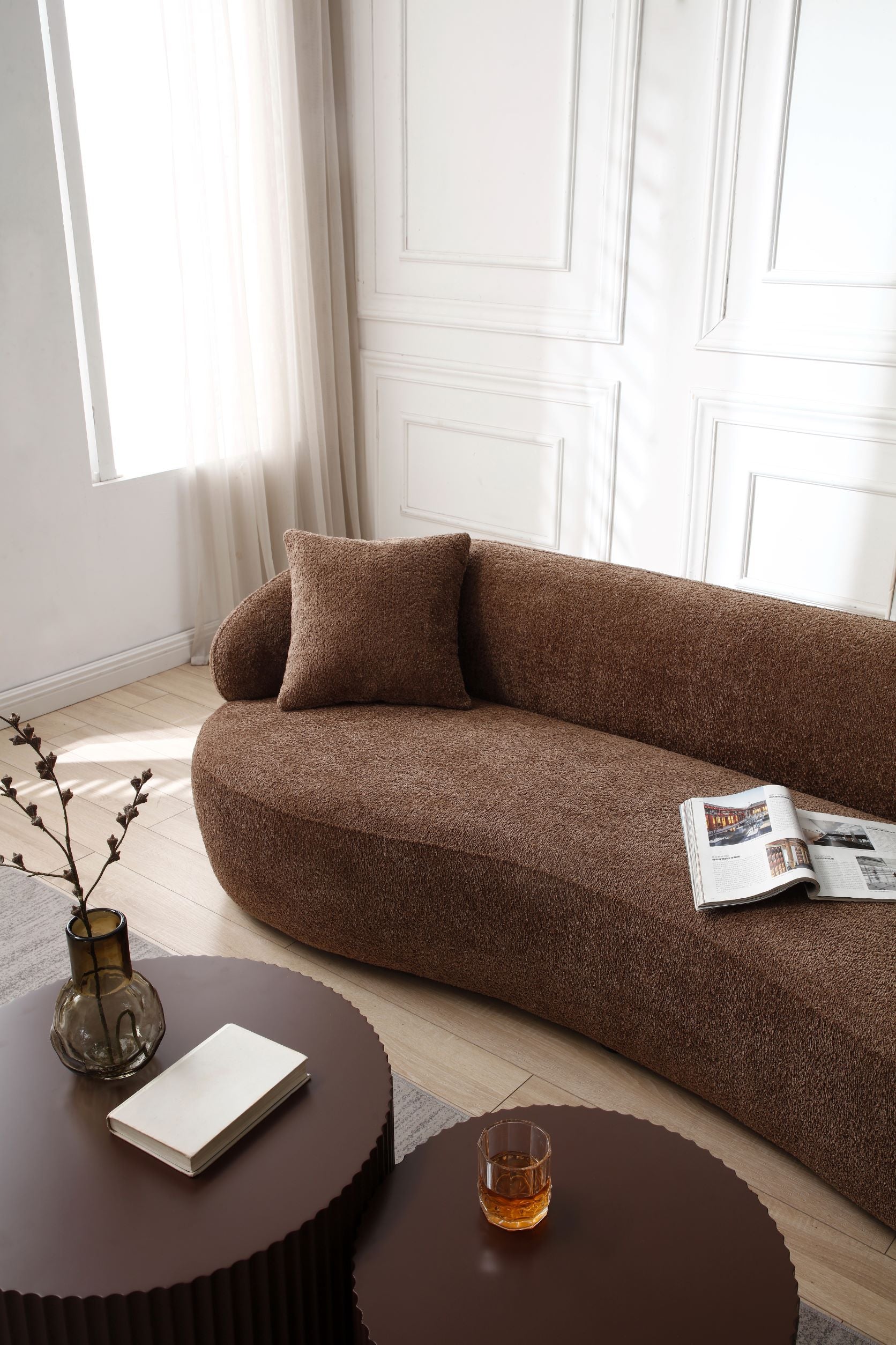 Textured brown boucl sofa with a modern curved design and accent pillow