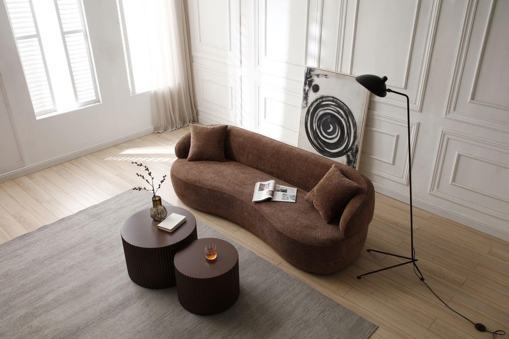 Brown boucl fabric curved sofa with accent pillows and a magazine