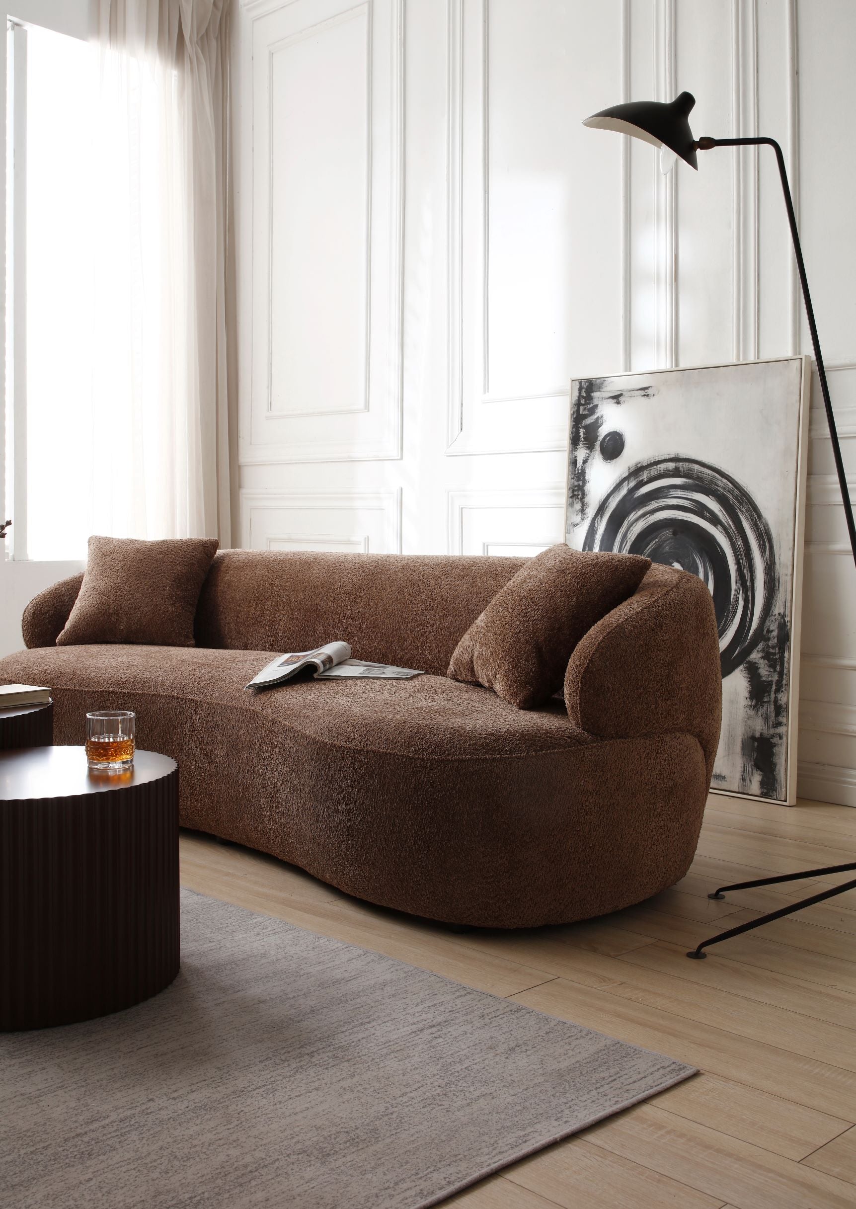 Curved brown boucle fabric sofa with textured upholstery and matching throw pillows