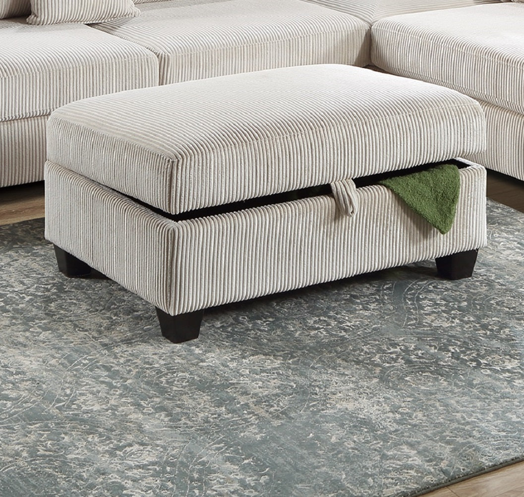 Cream corduroy storage ottoman with dark wood legs and green throw inside