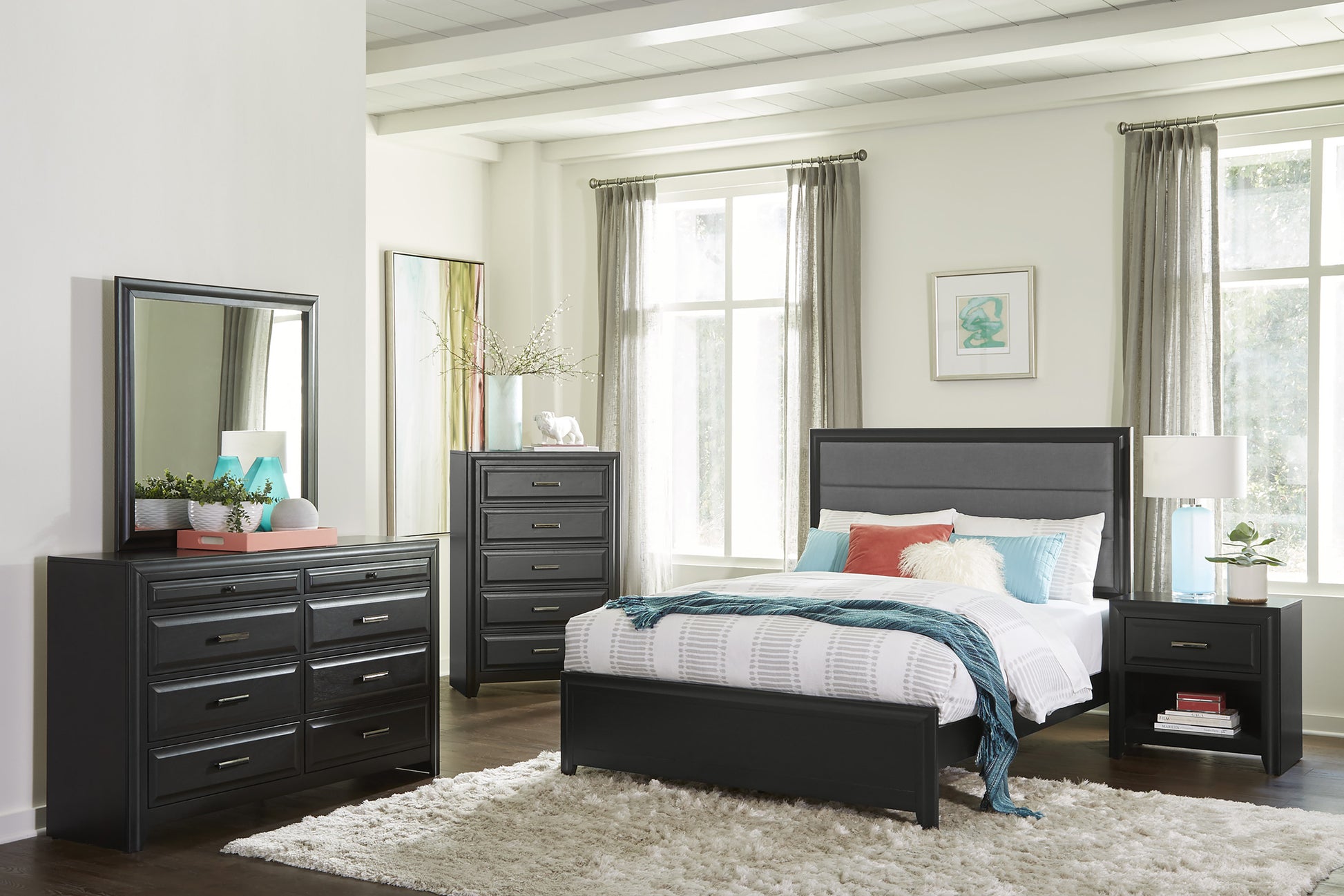 Dark gray upholstered queen bed with patterned bedding and teal throw