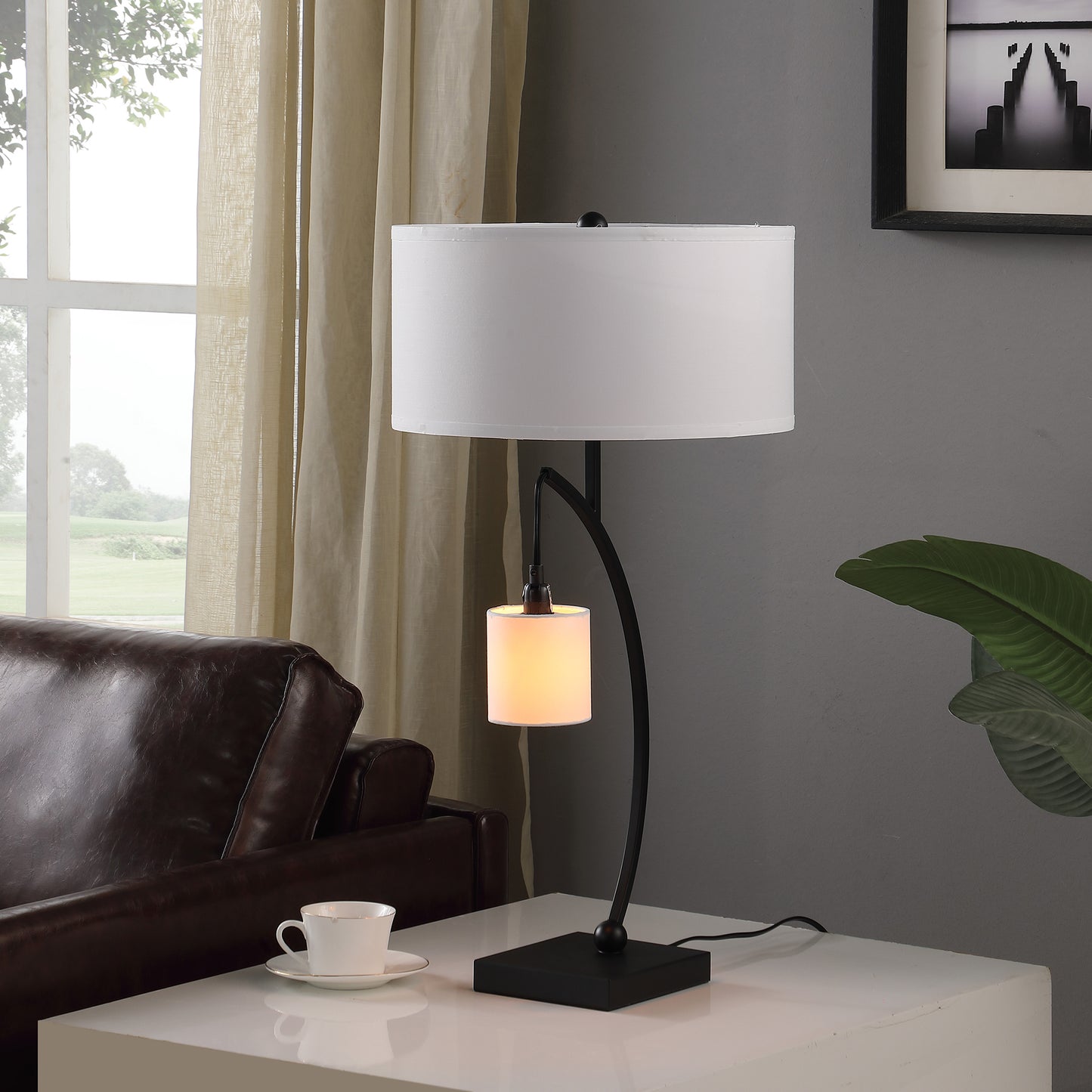 Black modern desk lamp with white drum shade and curved arm holding accent light