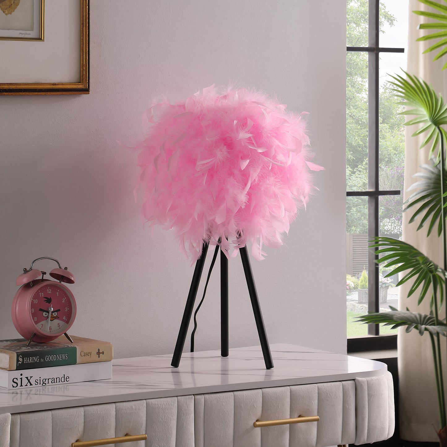 Fluffy pink feather table lamp with a black tripod base creating a whimsical accent for any room