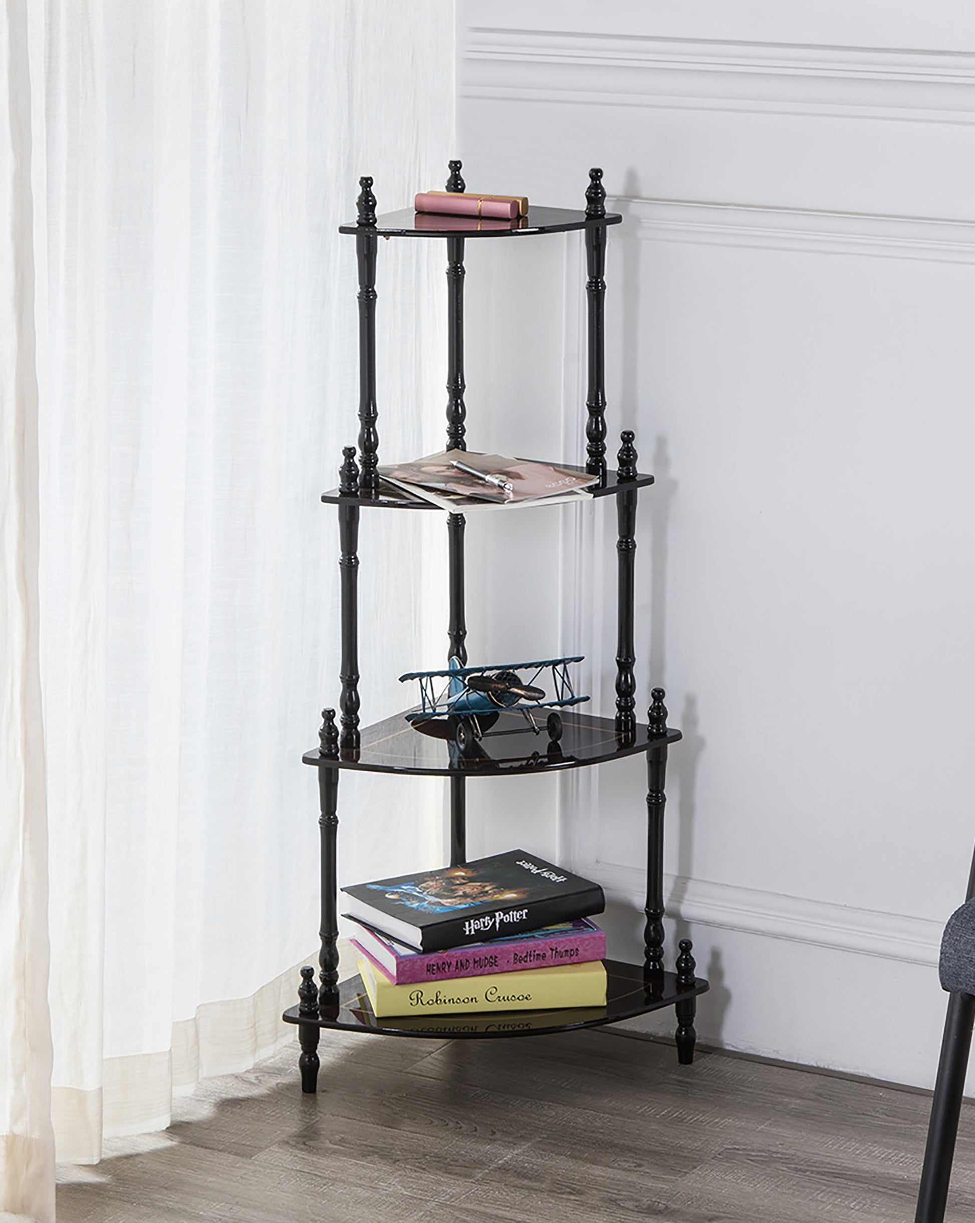 Black tier corner shelf unit with decorative finials holding books and model airplane