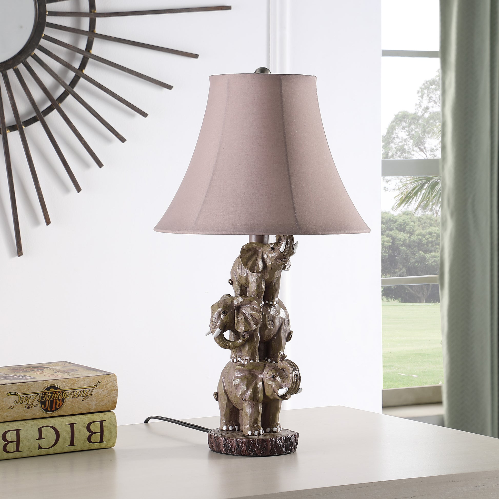A decorative table lamp with a stacked elephant base in bronze and a taupe fabric shade