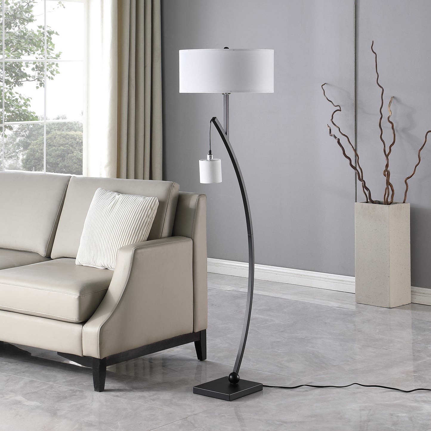 Modern black arc floor lamp with white drum shade and reading light complementing a living room sofa