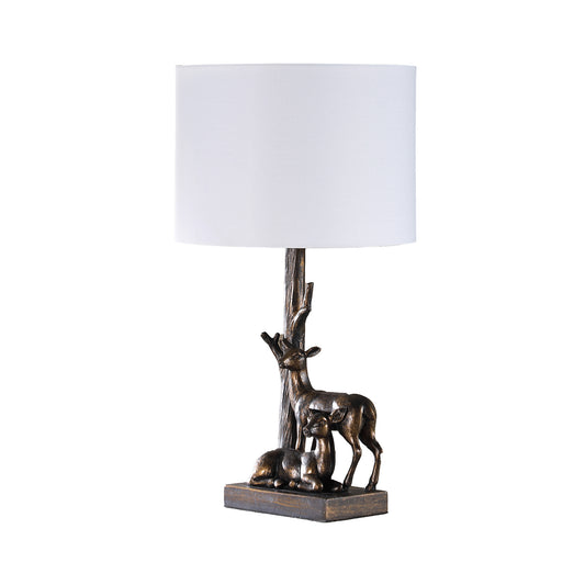 Bronze deer table lamp with a white linen shade and realistic tree trunk base