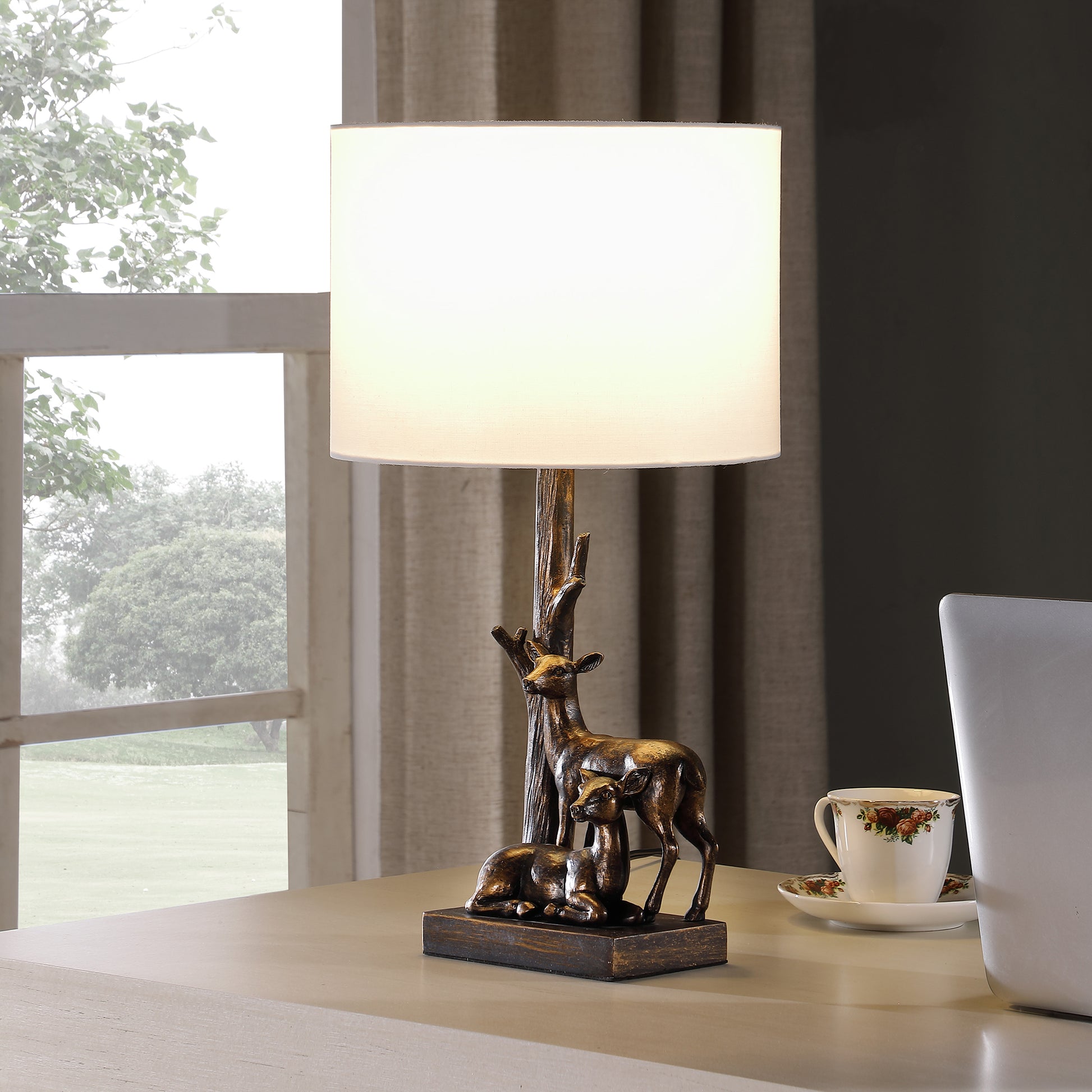 Bronze table lamp with deer figurine base and cream shade for a rustic accent