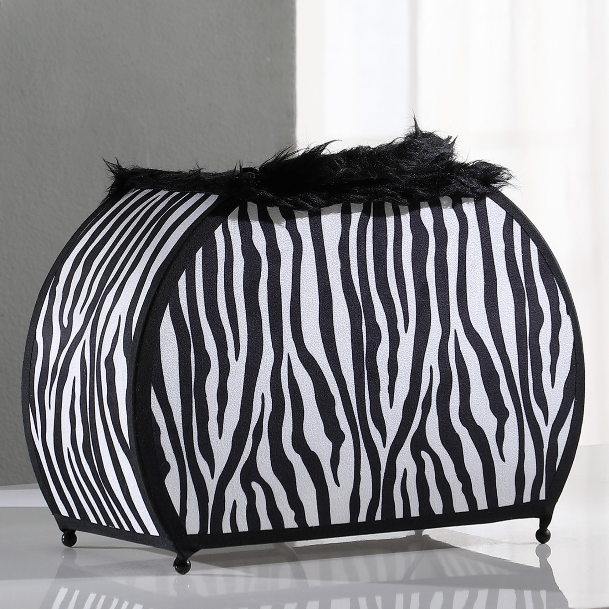 Black and white zebra print fabric storage ottoman with black furry trim