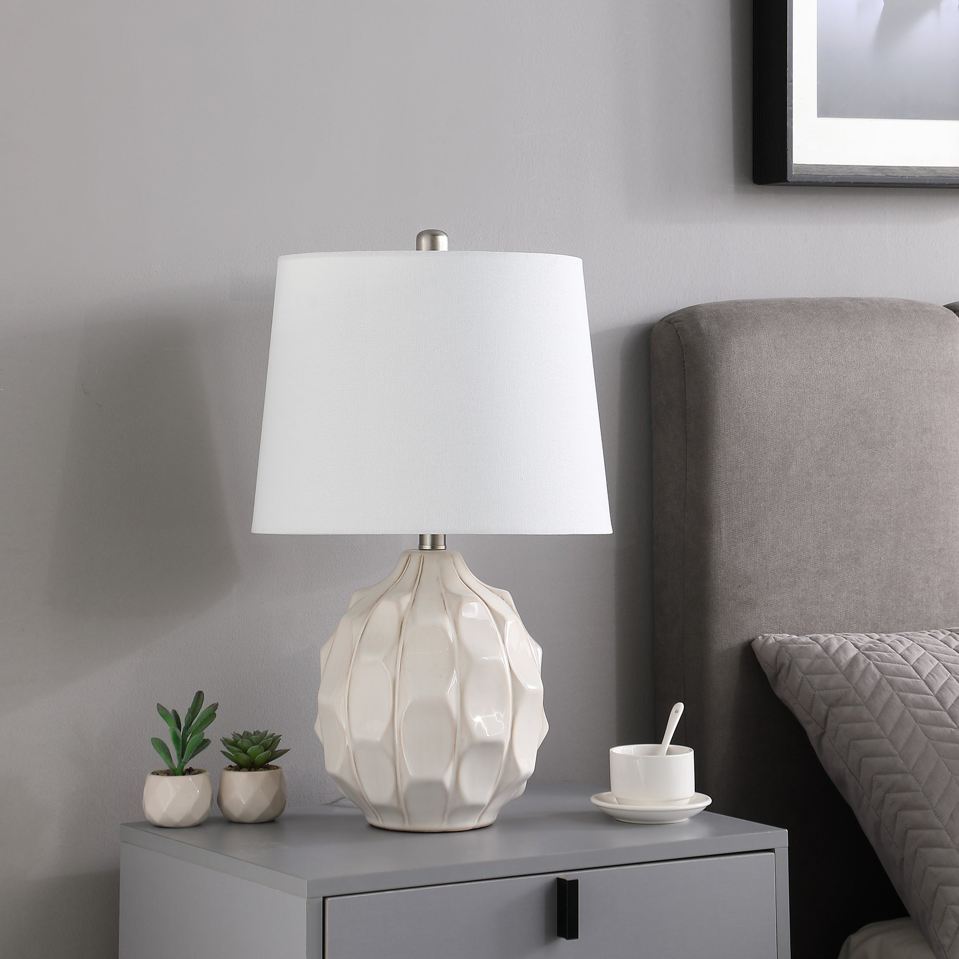 Cream ceramic table lamp with textured base and white drum shade for bedside