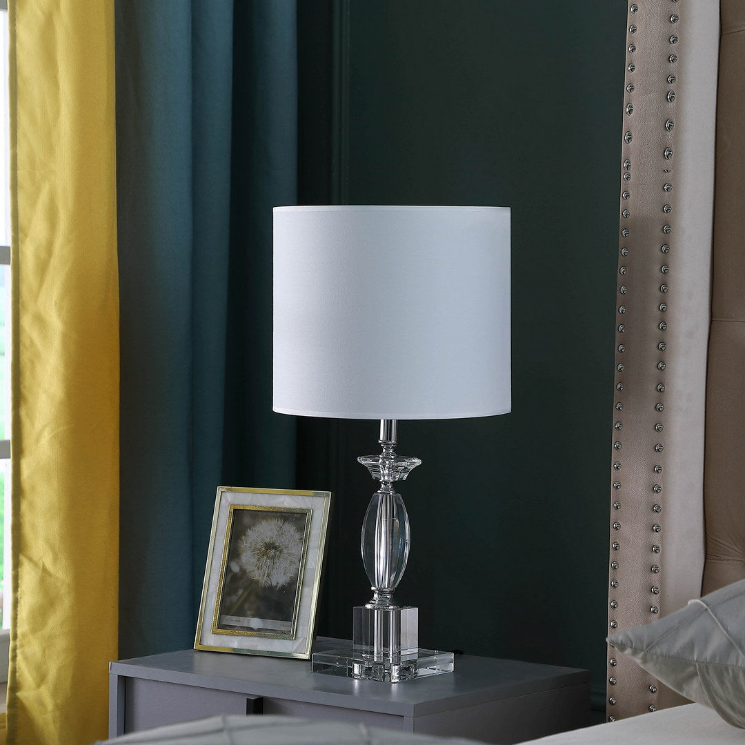 Elegant crystal table lamp with a white drum shade and polished metal accents
