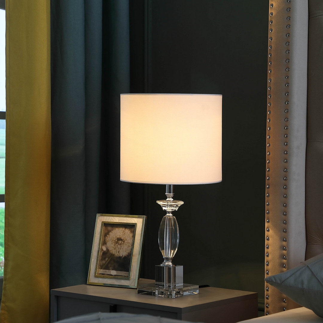Elegant crystal table lamp with a white drum shade on a nightstand