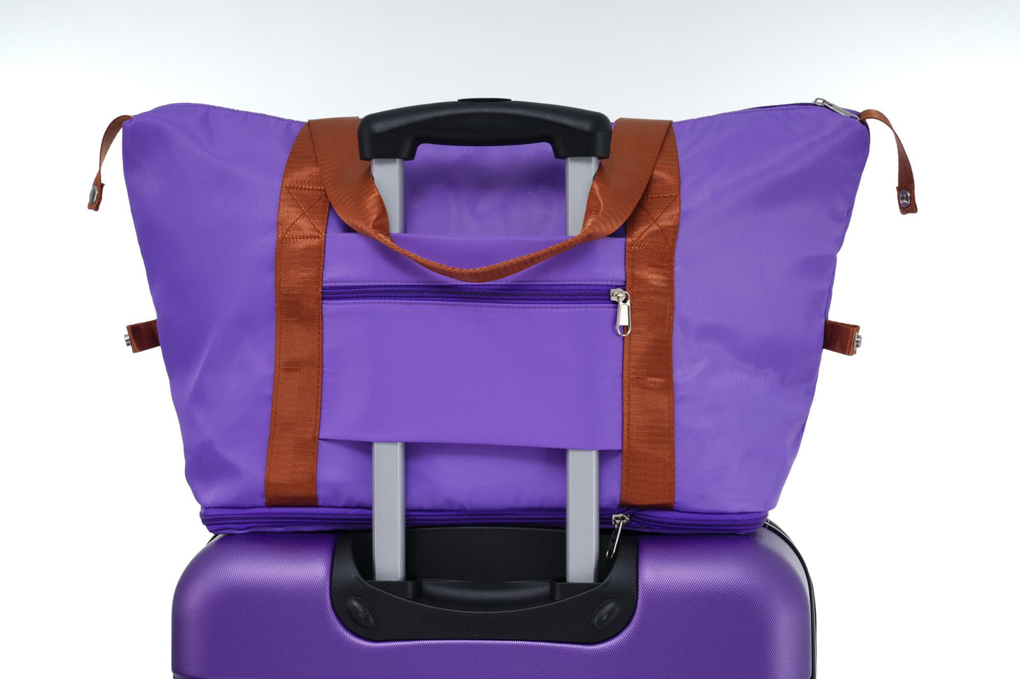 Purple duffel bag with brown straps stacked on a purple hardside suitcase ready for travel