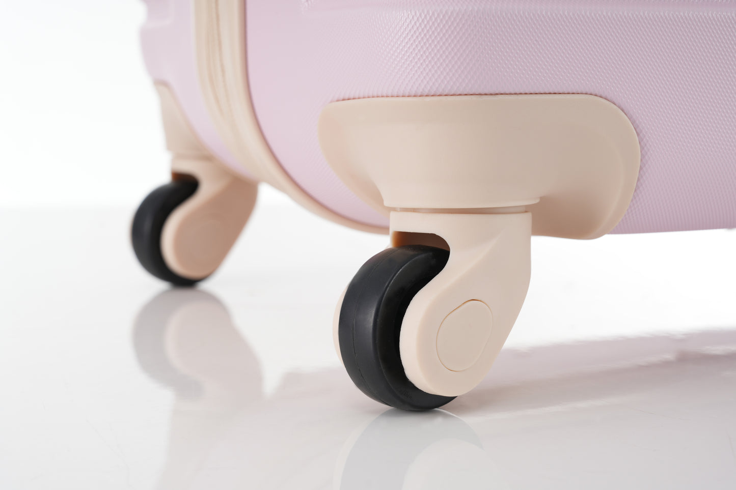 Closeup of pink textured hardshell suitcase wheels on a white background