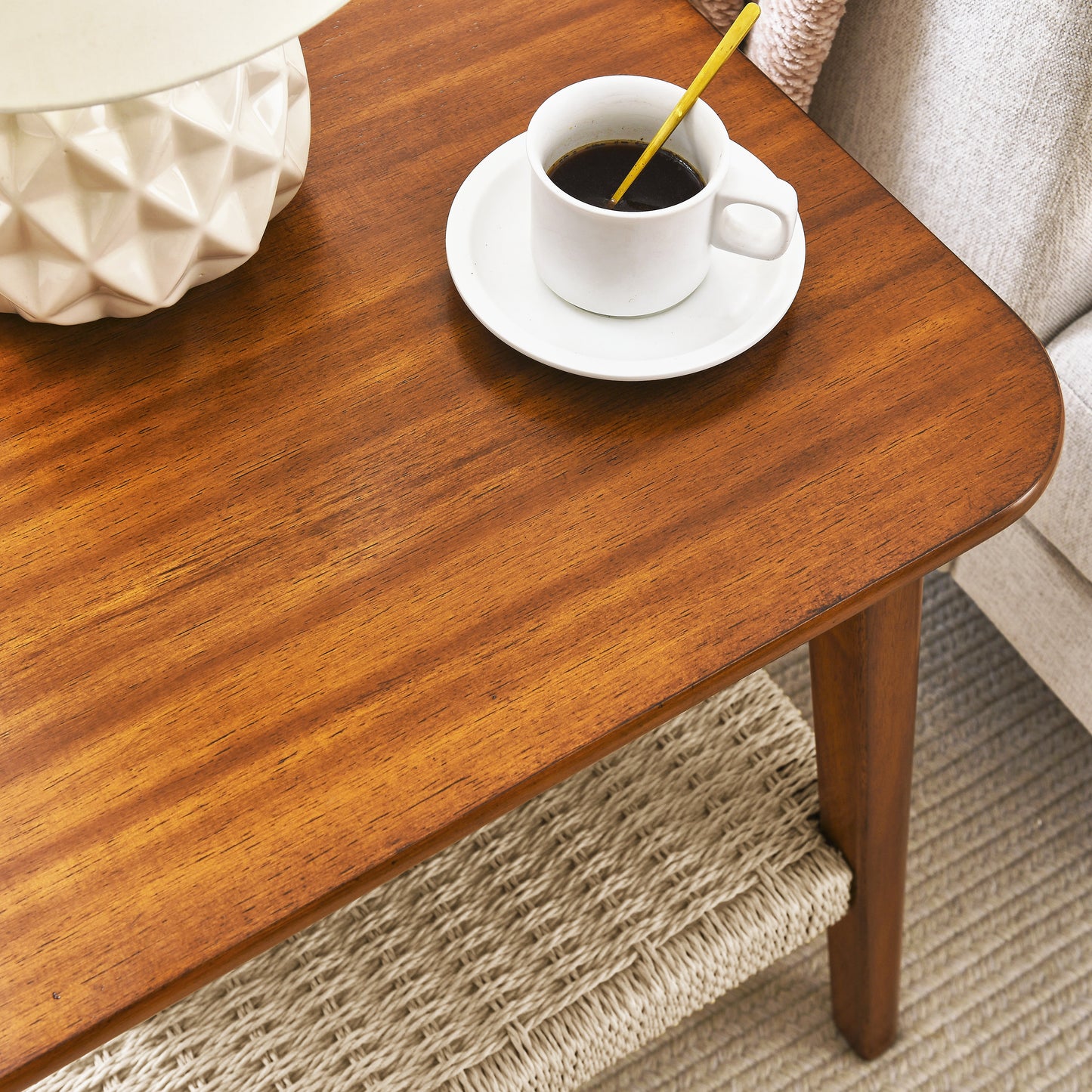 Midcentury modern walnut coffee table with a textured white vase and black coffee cup