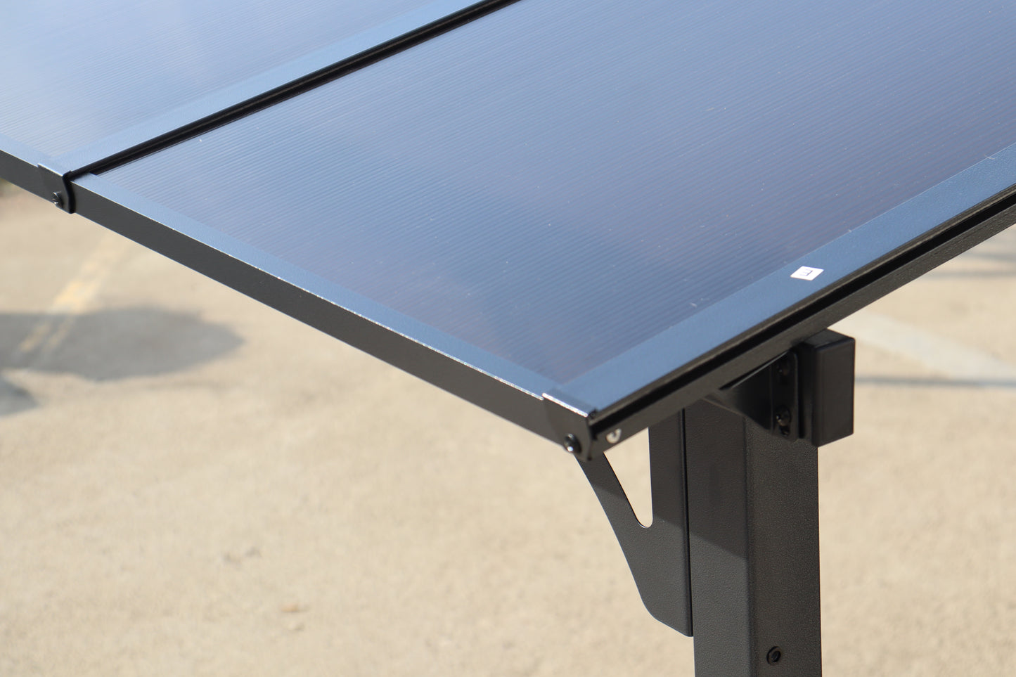 Closeup of a dark ribbed polycarbonate panel with a black metal frame ideal for roofing solutions