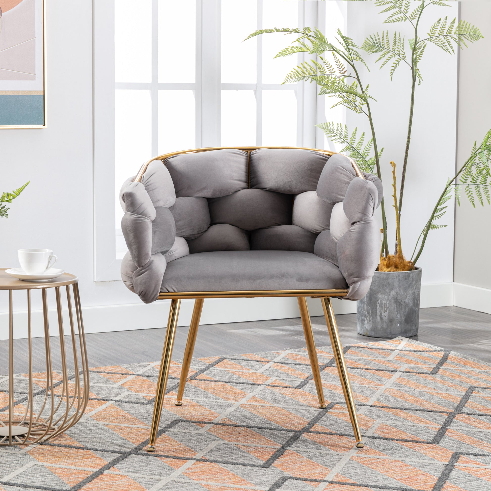 Grey velvet armchair with tufted seat and gold legs