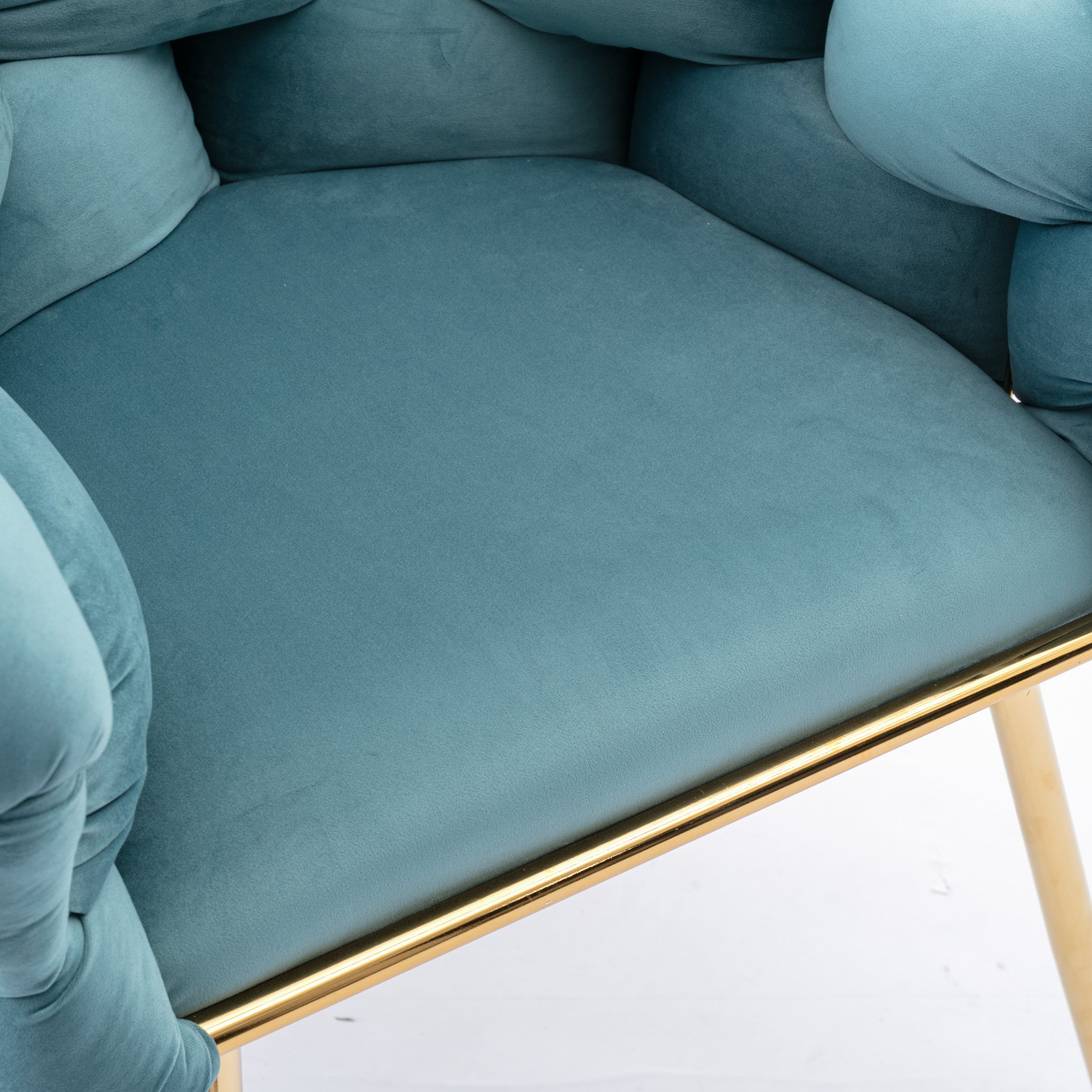 Closeup of a plush teal velvet accent chair with gold trim and legs