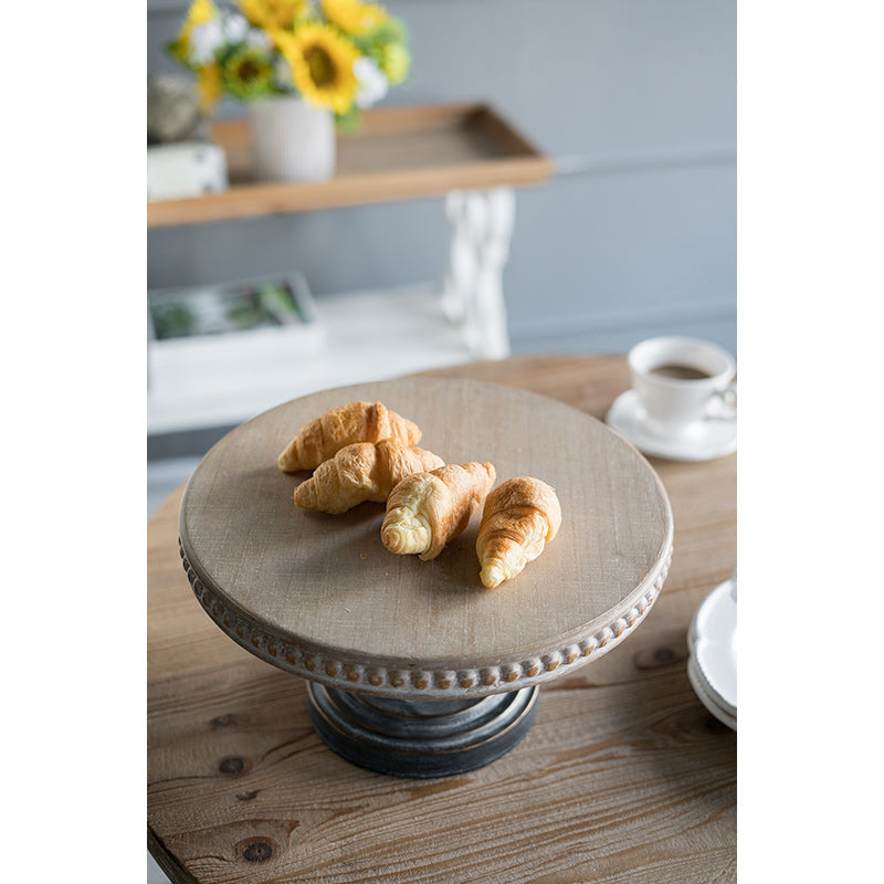 Rustic wooden cake stand with beaded edge displays fresh croissants