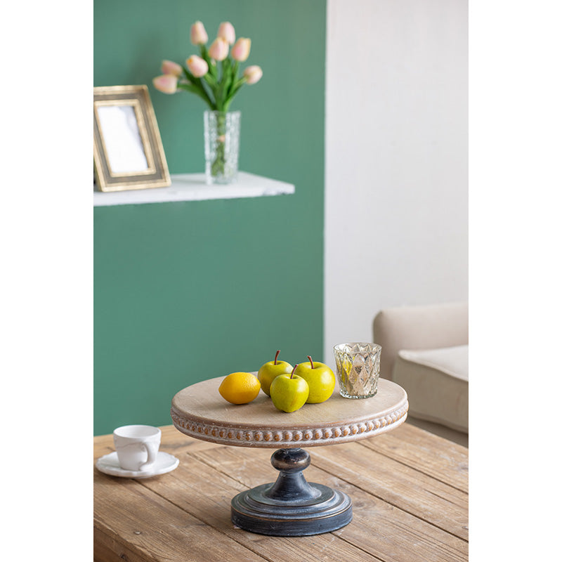 Rustic wooden cake stand with beaded edge displaying faux apples and lemon