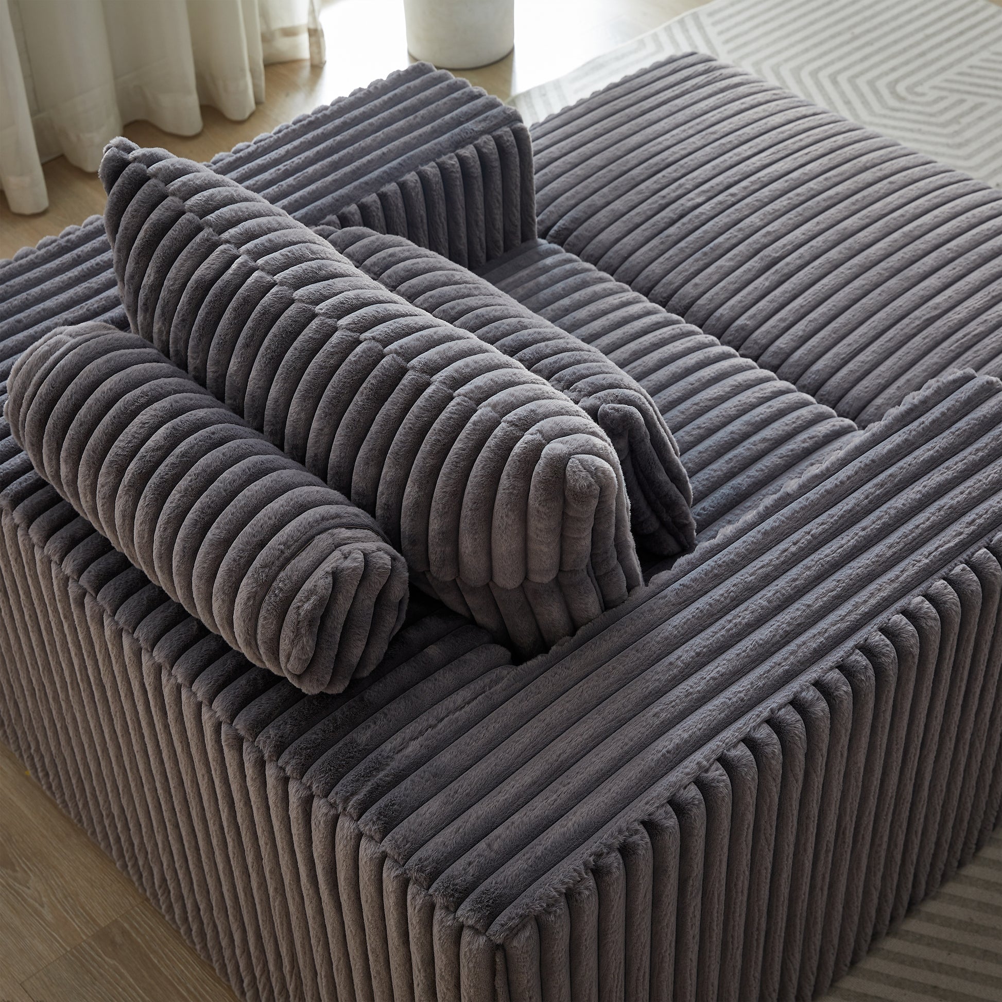 Plush corduroy modular sofa in dark grey featuring comfortable cylinder pillows for ultimate relaxation