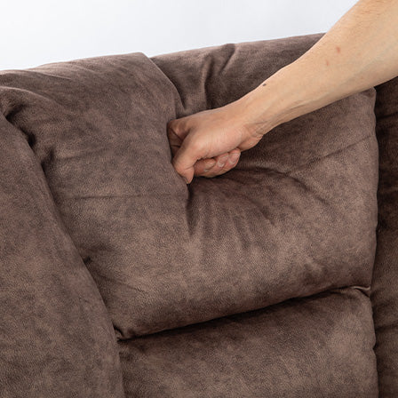 Hand pressing into plush brown sofa cushion highlighting softness