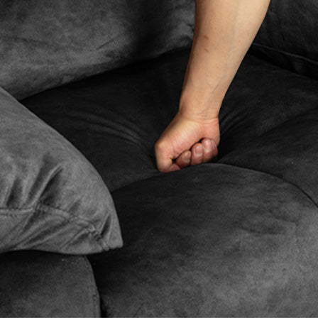 Hand pressing into plush gray sofa cushion showcasing comfort and depth