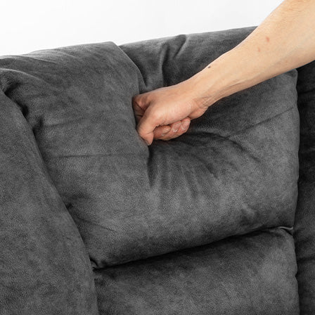 Closeup of a hand indenting a plush charcoal grey sofa cushion showcasing comfort