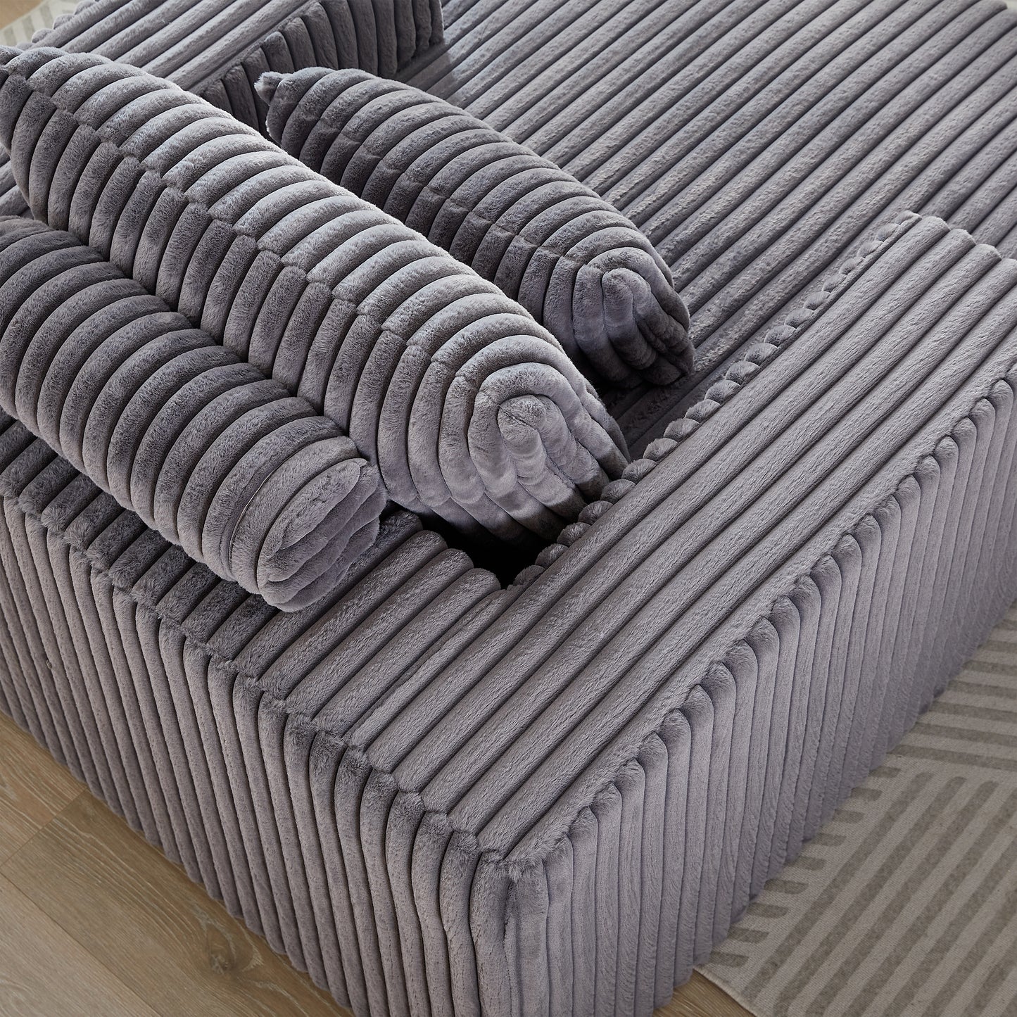 Closeup of plush grey corduroy sofa cushions with rounded bolster pillows