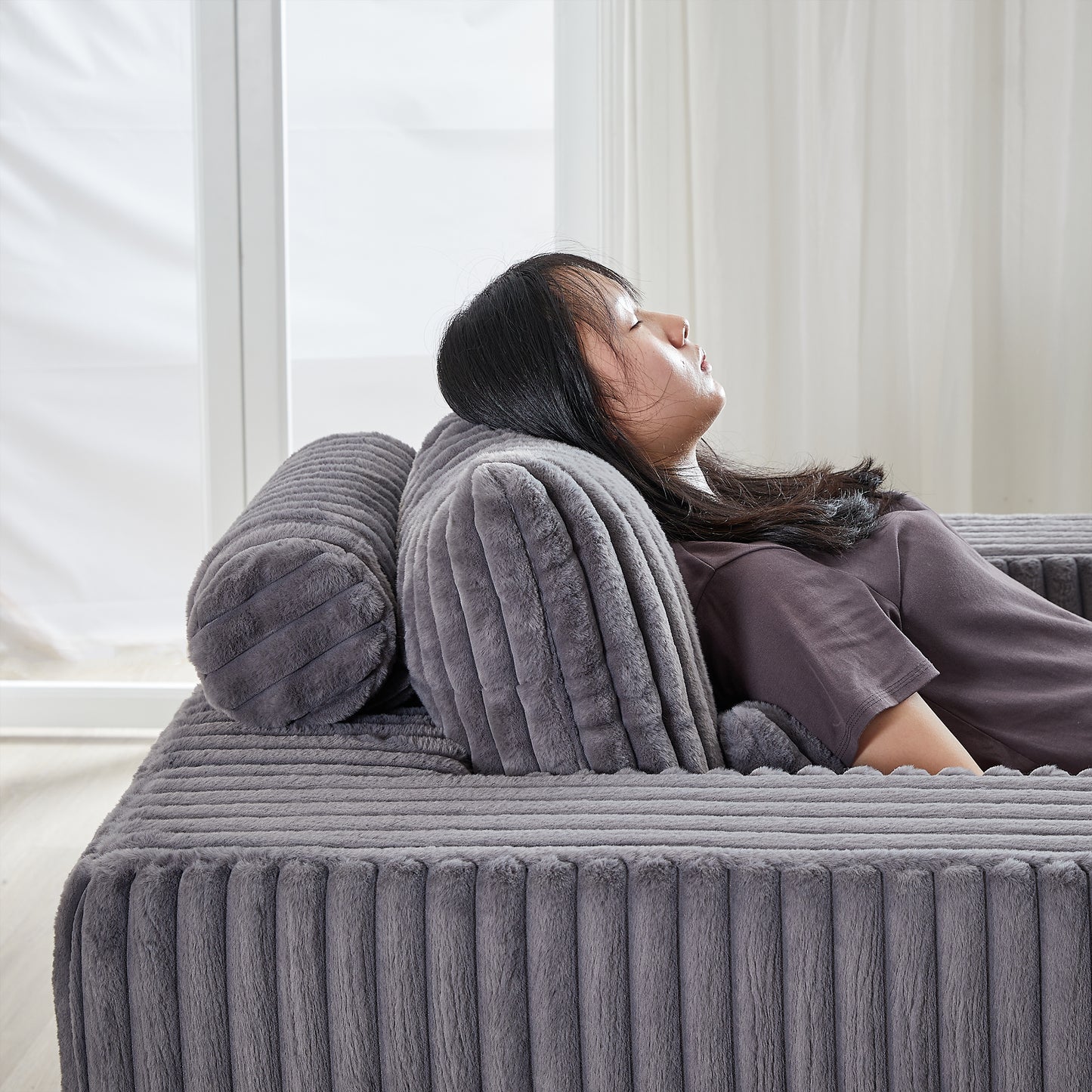 Plush gray floor sofa with comfortable back cushions and bolster pillow for relaxation