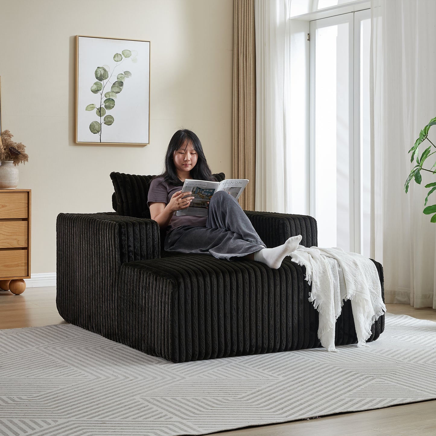 Black corduroy modular armchair with chaise lounge and white throw blanket