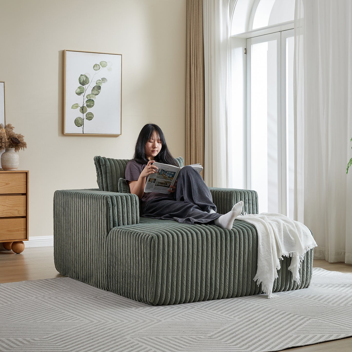 Green corduroy modular sofa with chaise and throw blanket