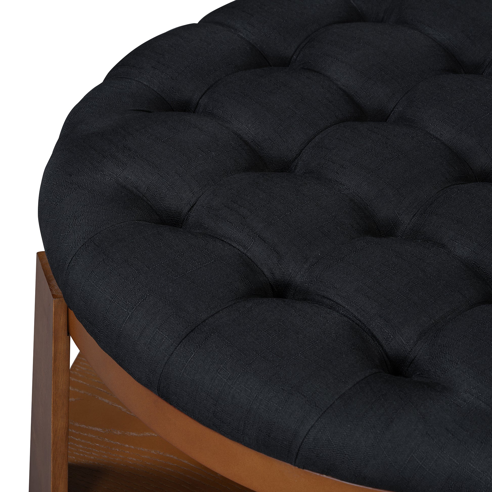 Closeup of a black tufted linen ottoman with wooden base