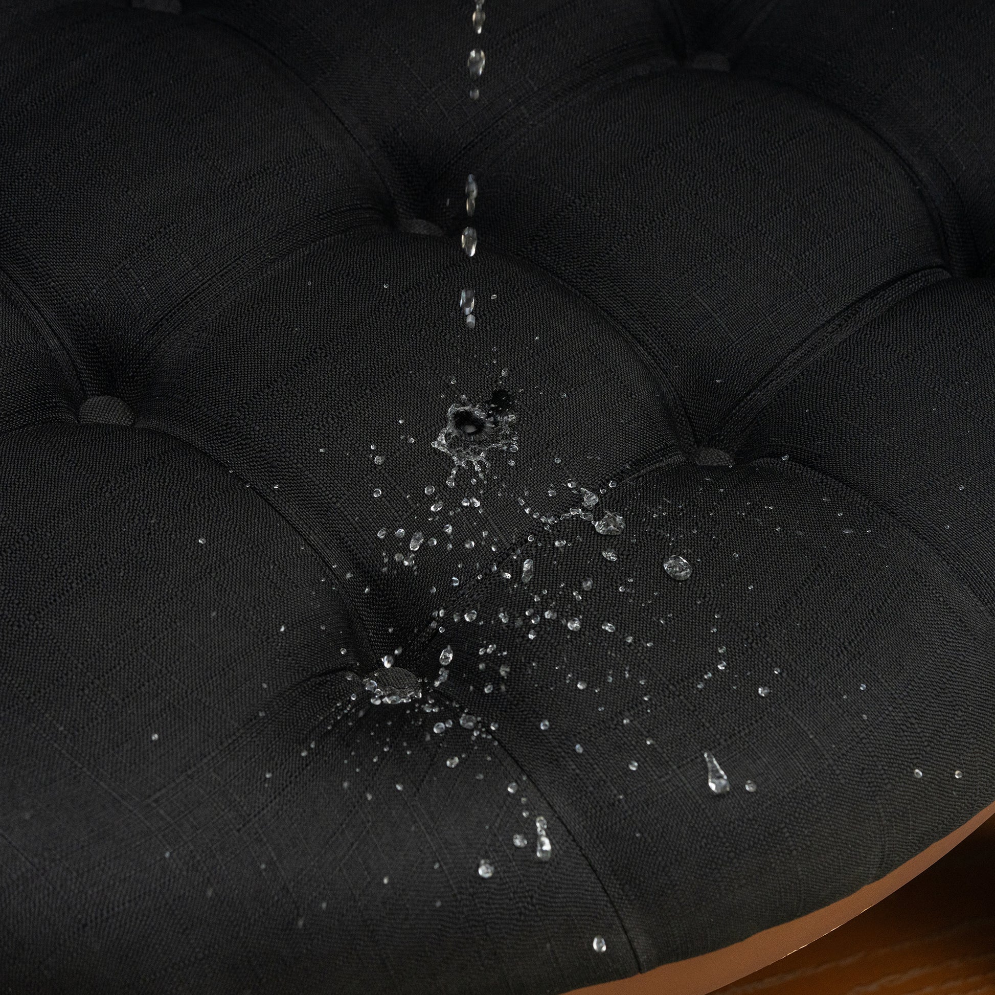 Black tufted fabric with water droplets showing its waterresistant quality