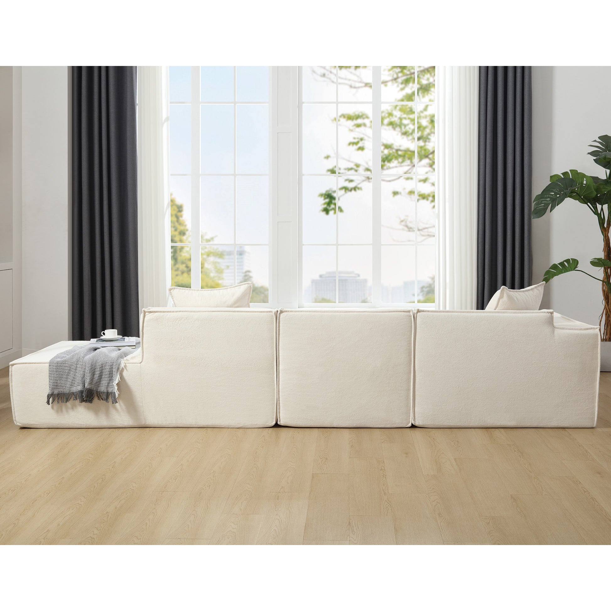 Cream boucle modular sofa with plush texture accent blanket and throw pillows on light wood floor