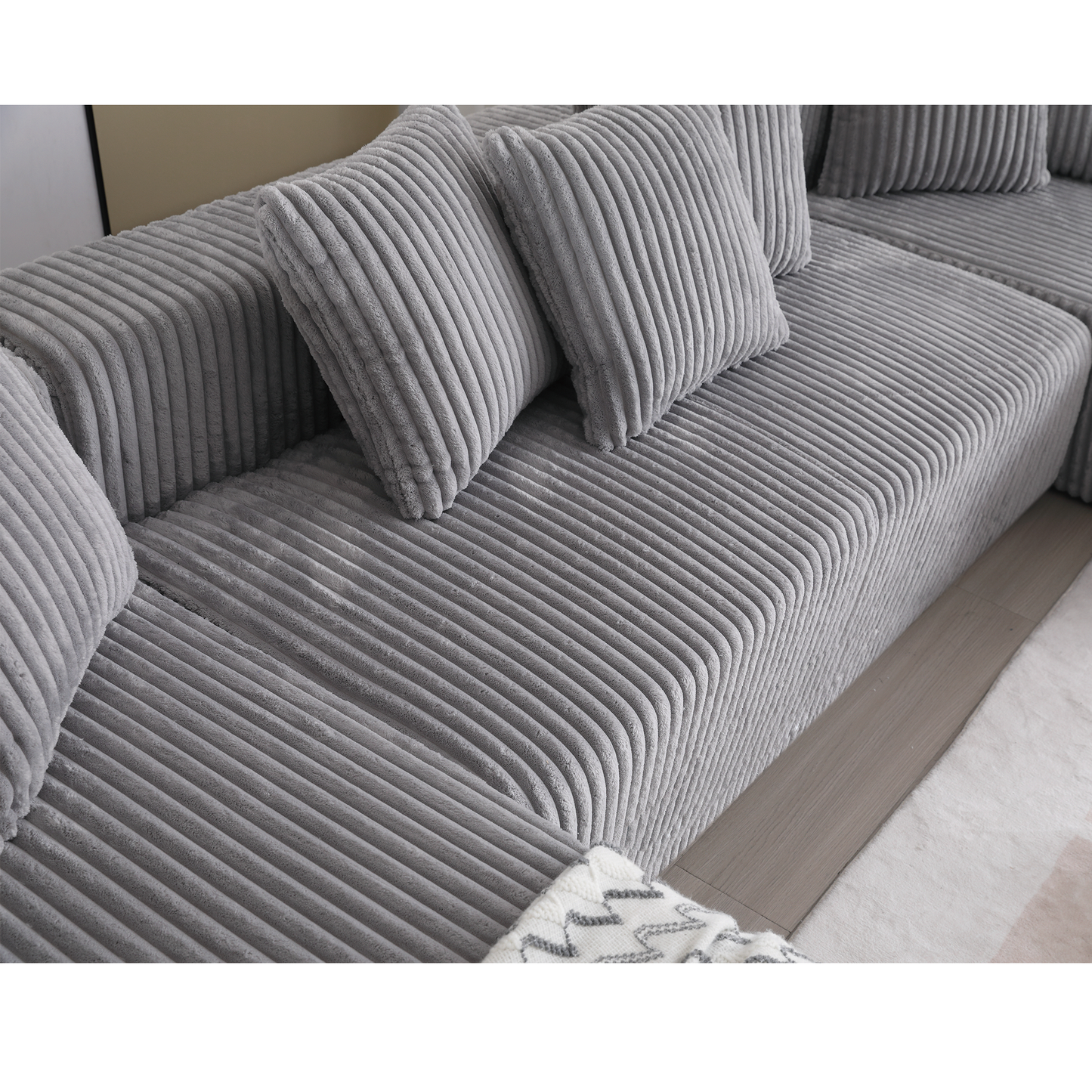 Closeup of a grey corduroy sofa with plush cushions showcasing its texture