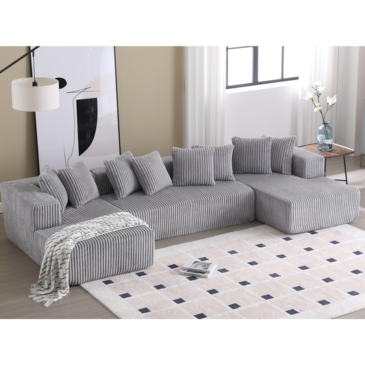 Plush grey corduroy sectional sofa with matching throw pillows and an ottoman