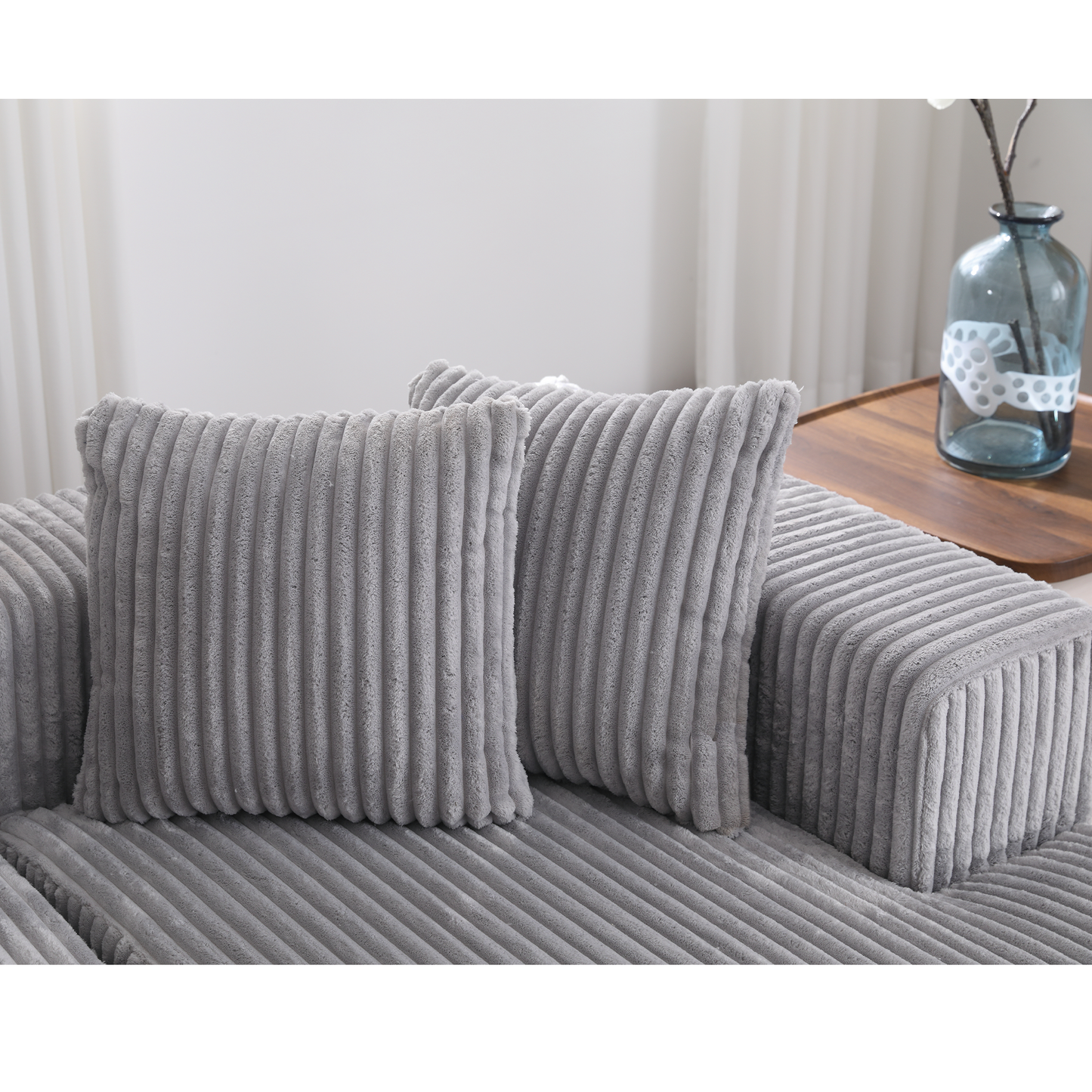 Two plush grey corduroy throw pillows on a matching sofa