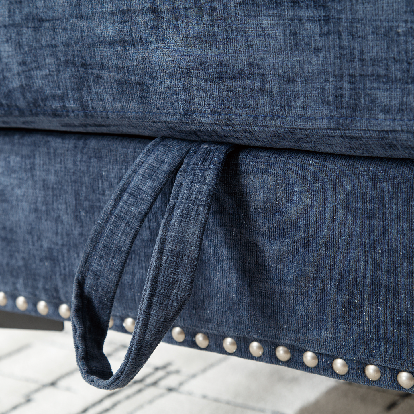 Close up of textured navy blue fabric on a sofa with silver studding